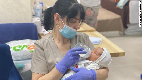 Una niñera en una clínica de subrogación alimenta a un bebé recién nacido que espera ser recogido por sus nuevos padres.