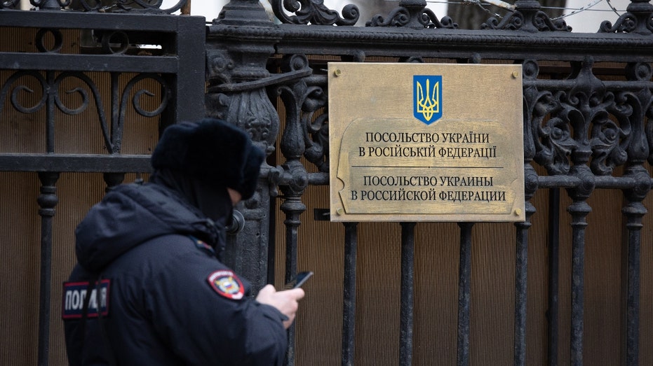 Un oficial de policía revisa su teléfono inteligente mientras patrulla en la puerta de entrada del edificio de la Embajada de Ucrania en Moscú, Rusia, el jueves 24 de febrero de 2022. Fotógrafo: Andrey Rudakov/Bloomberg