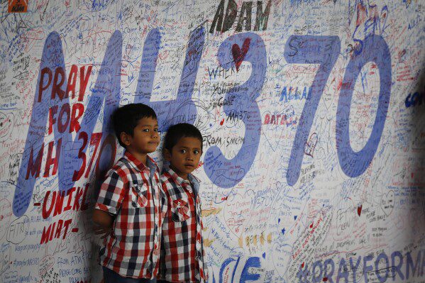 ARCHIVO - Dos niños malasios parados frente a un tablero de mensajes y extienden sus mejores deseos a las personas involucradas en la desaparición del vuelo MH370 de Malaysia Airlines, en Sepang, Malasia, el 16 de marzo de 2014. Hace diez años, el vuelo 370 de Malaysia Airlines, que había desaparecido el 8 de marzo, había desaparecido en 2014 mientras se dirigía de Kuala Lumpur a Beijing con más de 200 personas a bordo.  (Foto AP/Vincent Thean, archivo)