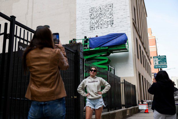 Nicole Granato toma una foto de Peyton Granato frente a un mural con código QR en River North el 16 de abril de 2024. El código QR enlaza con la página web de Taylor Swift.  (Eileen T. Meslar/Chicago Tribune)