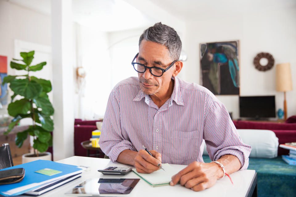 Hombre maduro con gafas trabajando en finanzas personales en casa