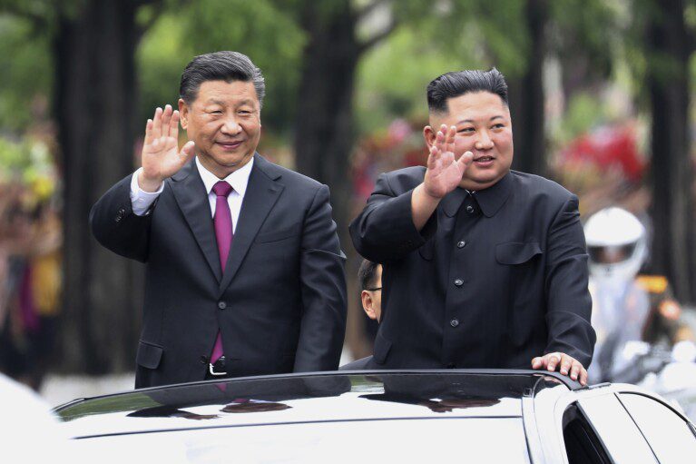 ARCHIVO - En esta fotografía de archivo del 20 de junio de 2019 publicada por la agencia de noticias china Xinhua, el presidente chino Xi Jinping, izquierda, de visita, y el líder norcoreano Kim Jong Un saludan desde una limusina abierta mientras viajan por una calle en Pyongyang, Corea del Norte.  China parece estar manteniendo la distancia mientras Rusia y Corea del Norte se acercan con un nuevo pacto de defensa que podría inclinar el equilibrio de poder entre los tres países autoritarios.  (Ju Peng/Xinhua vía AP, archivo)