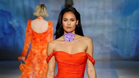 Getty Images Una modelo camina por la pasarela del desfile de Shein con una camisa naranja.