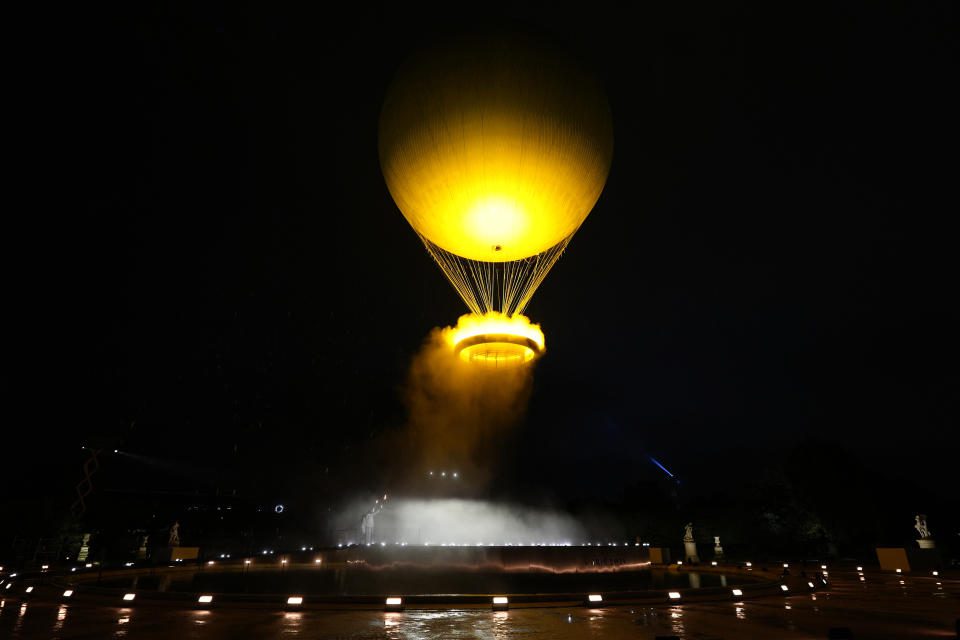 Teddy Renner y Marie-Josée Perec observan cómo se eleva el pebetero en un globo en París, Francia, durante la ceremonia de apertura de los Juegos Olímpicos de Verano de 2024, el viernes 26 de julio de 2024. (Foto AP/David Goldman)