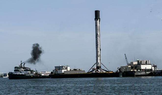 Los espectadores observan cómo se inserta el propulsor de primera etapa de SpaceX en Puerto Cañaveral a bordo del barco Just Read the Instrucciones el 4 de julio de 2020.