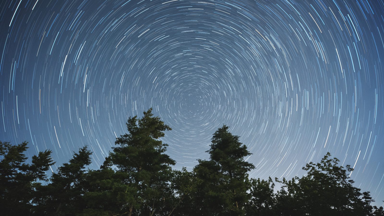 Líneas espirales de estrellas en el cielo nocturno causadas por la rotación de la Tierra