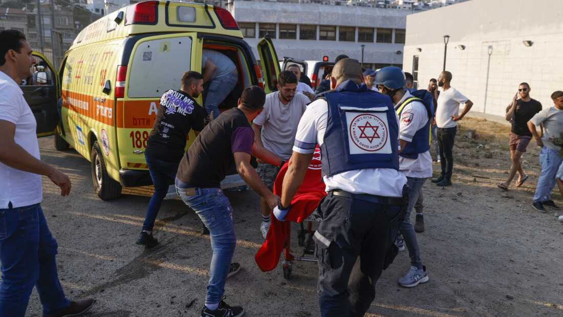 Las fuerzas de seguridad y los médicos israelíes transportan a las víctimas, junto con los residentes locales, al lugar de un ataque libanés en la aldea de Majdal Shams, en la región de los Altos del Golán controlada por Israel, el sábado.