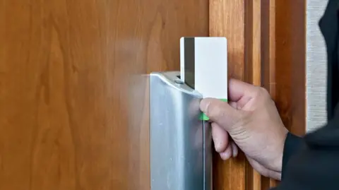 Getty Images Una mano desliza una tarjeta magnética a través de la cerradura de una puerta.